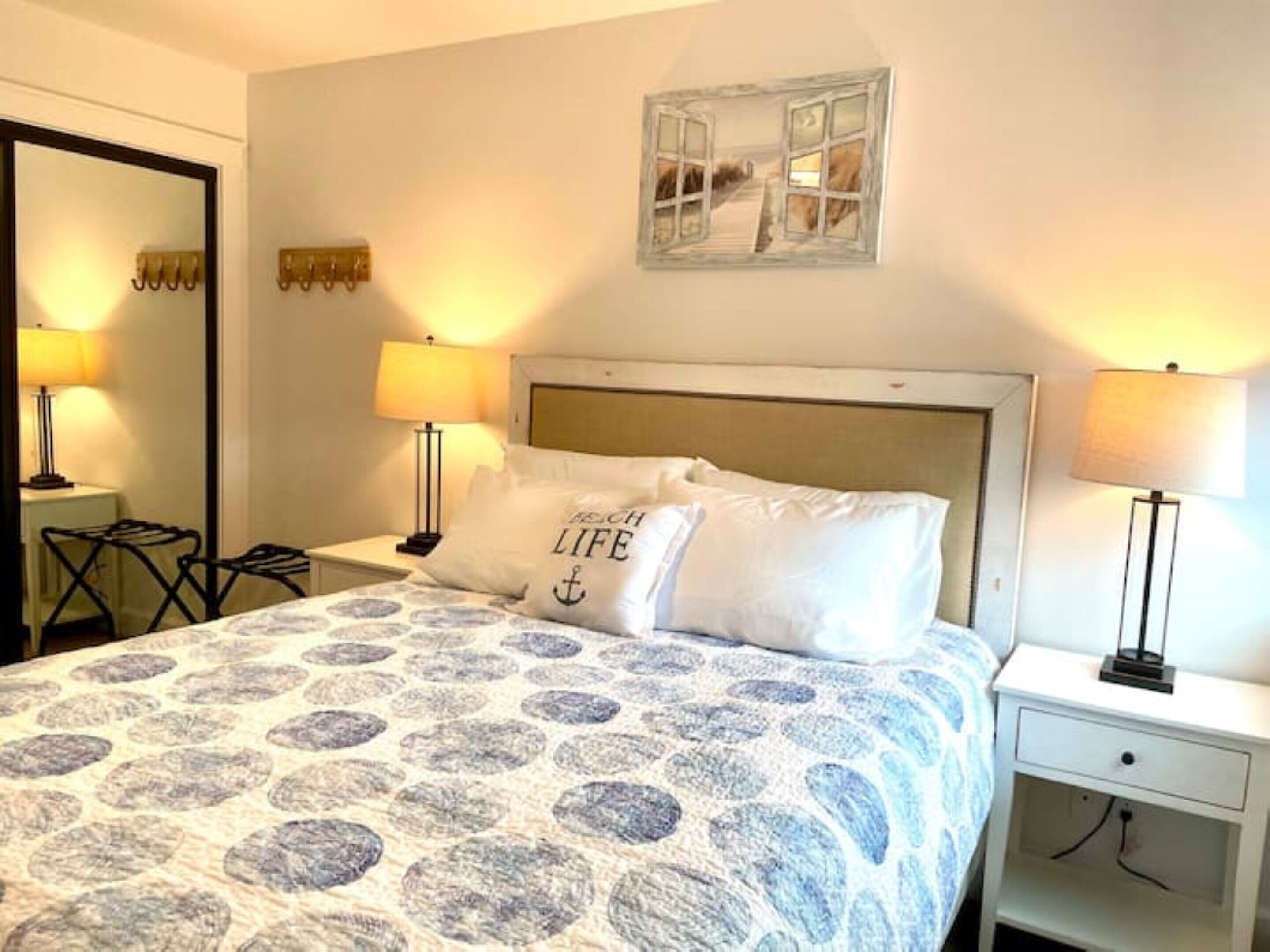 Un dormitorio ordenado con una cama, dos mesitas de noche y una mesilla.