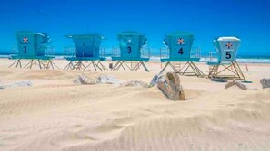 Lifeguard towers numbered 1 to 5 on a sandy beach with clear blue sky.