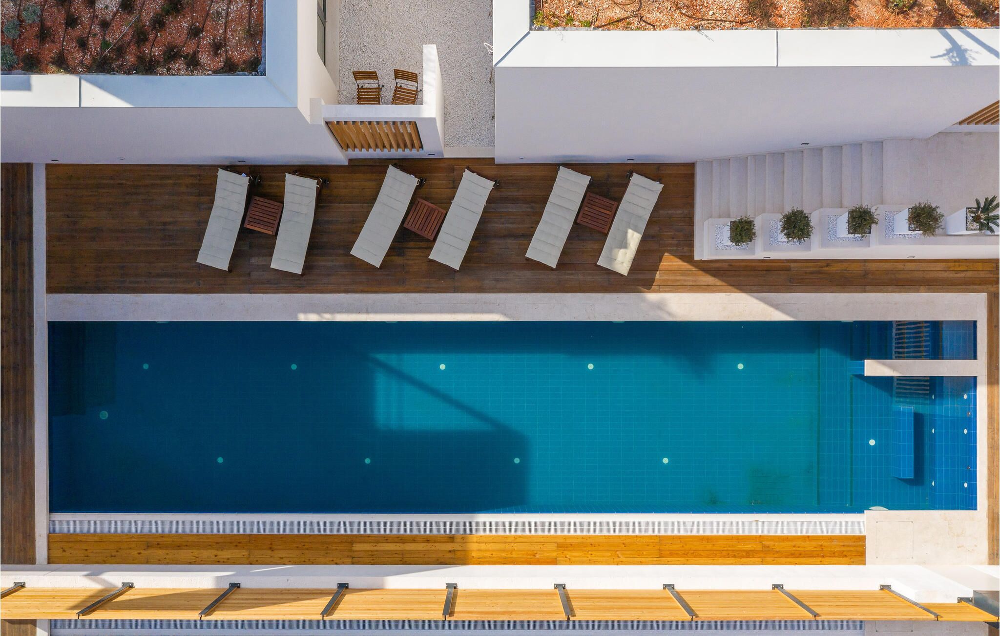 Une piscine sur le toit, dotée d’une terrasse en bois et de chaises longues.
