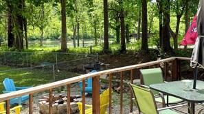 An outdoor seating area with a wooden deck, metal railing, and a table with chairs.