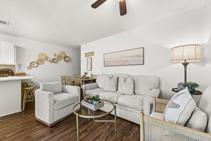 Ein Wohnzimmer mit einer Couch, Sesseln, einem Couchtisch und einem Essbereich mit Stühlen und einem kleinen Tisch.