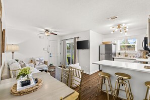 A modern kitchen with a central island, bar stools, and a dining area with a table and chairs.