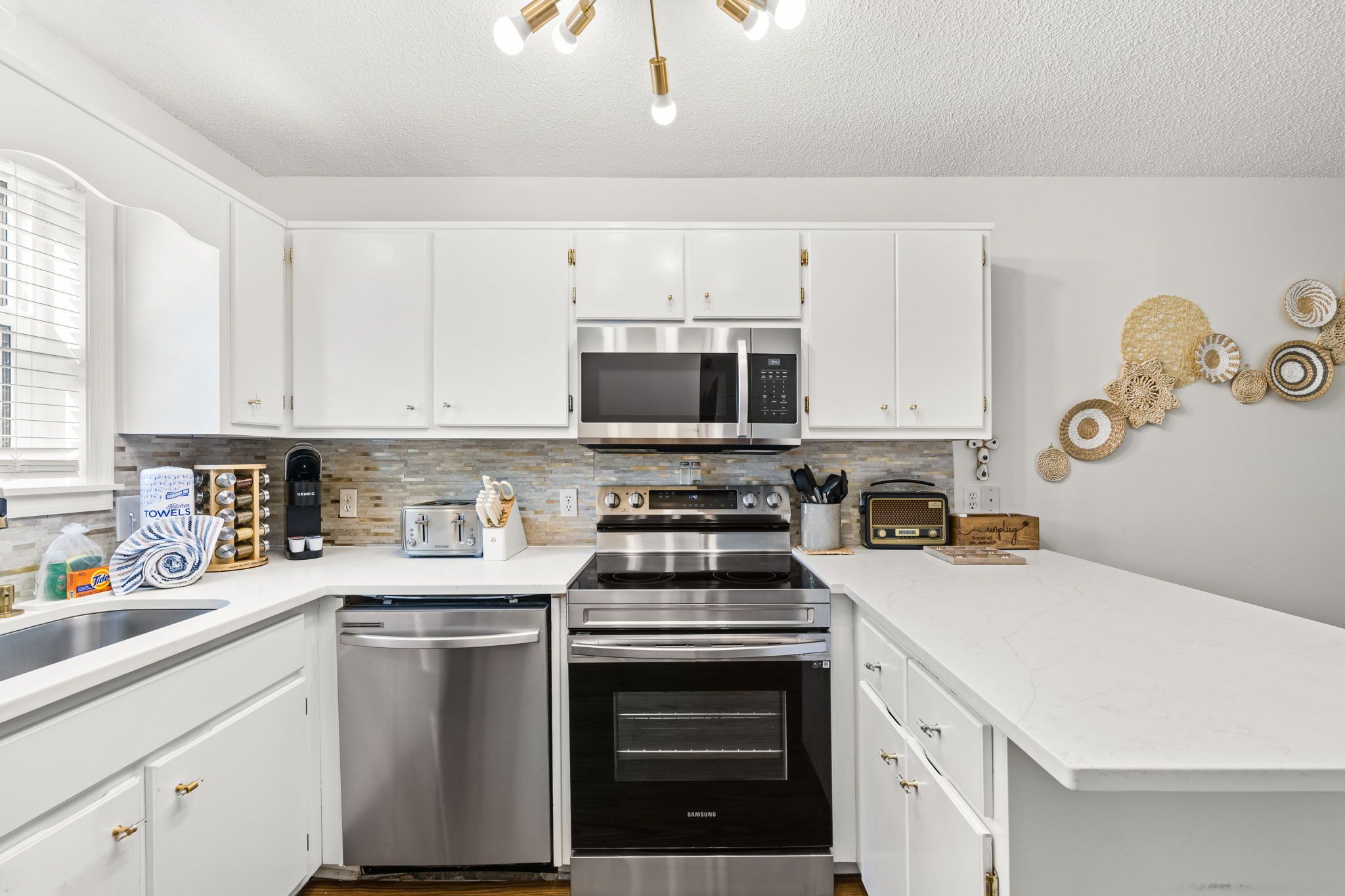 A modern kitchen with white cabinetry, stainless steel appliances, and a built-in microwave.