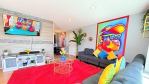 Un salon moderne avec un canapé gris, une moquette rouge et un téléviseur fixé au mur.