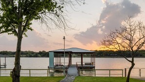 A gazebo with a metal roof and benches by a lake.