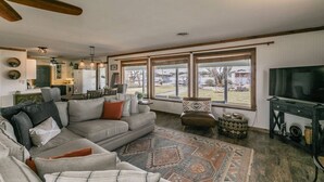 A spacious living room with a large gray sectional sofa, a patterned rug, and a television on a dark wooden stand.