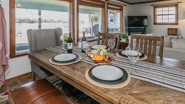 A dining area with a wooden table set for four, surrounded by chairs.