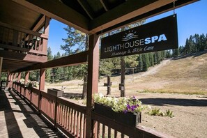 A wooden deck with a sign for Lighthouse Spa, featuring a view of a forested hillside.