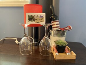 Une table avec deux verres à vin, une bougie rouge, une bouteille de vin, une petite plante et une boîte en bois avec une étiquette.