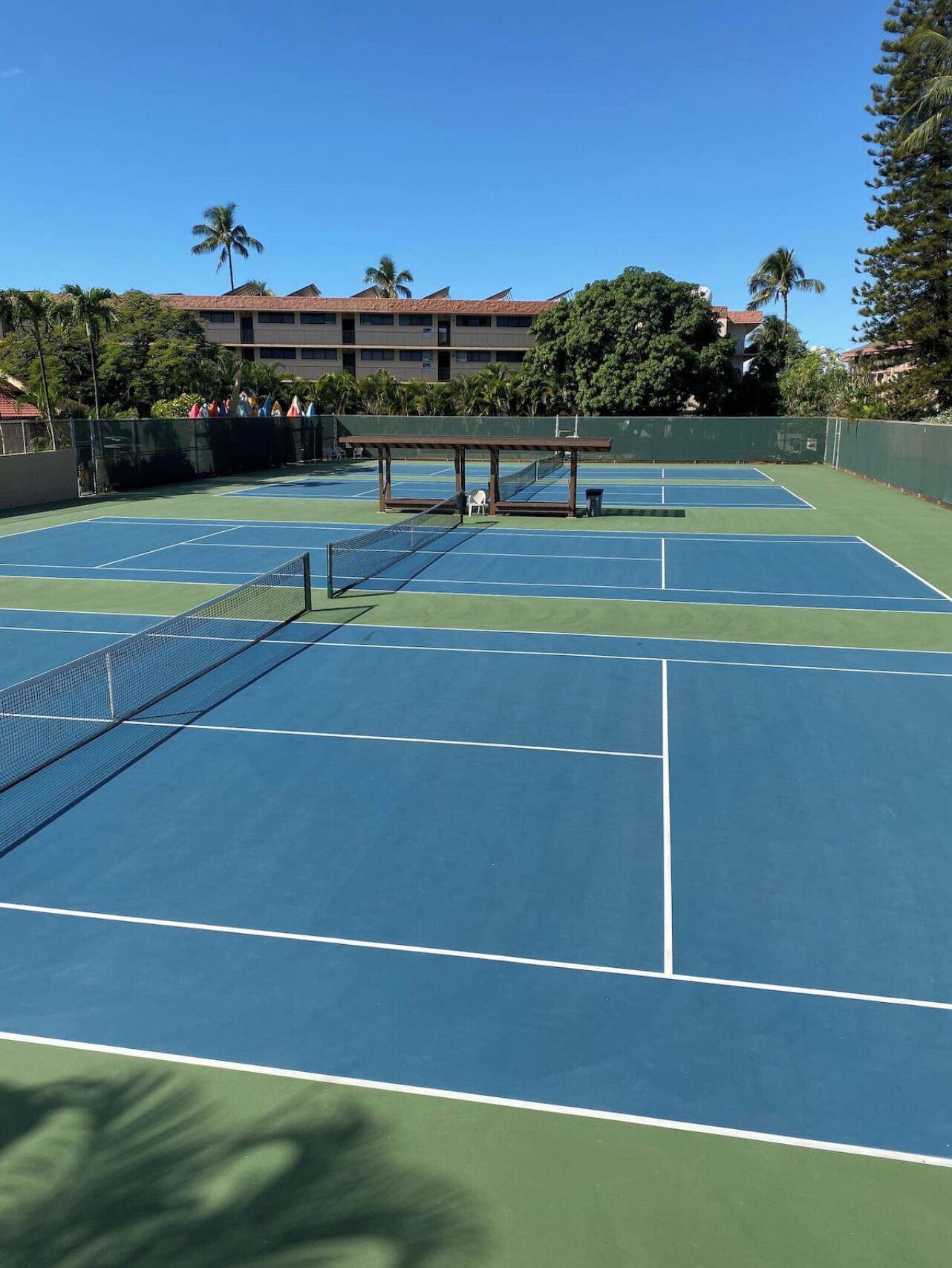 A tennis court with multiple courts, a net, and a seating area.
