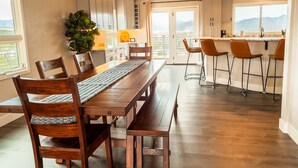 Una cocina moderna con una mesa de comedor de madera, taburetes de bar y vistas a la montaña.
