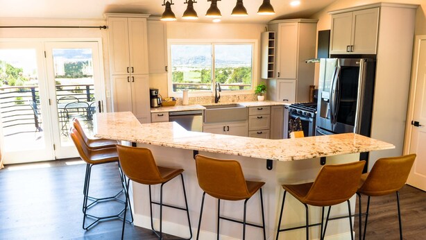 Una cocina moderna con una isla grande, taburetes de bar y vistas al exterior.