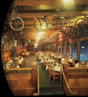 Guests can dine in a warm, inviting atmosphere with wooden tables and chairs, surrounded by large windows and unique bicycle wheel decor.