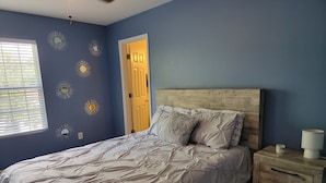 A bedroom with a bed, nightstand, and wall decor. - Cozy townhouse, close to downtown. (Durham)