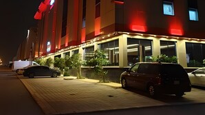 Un hôtel reconnaissable à son grand panneau « PARK », doté d’un design moderne avec des touches d’éclairage rouge et d’une série de fenêtres le long de la façade.
