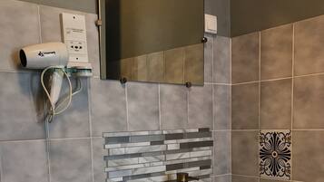 A bathroom with a white sink, a towel rack, a mirror, and a hairdryer on the wall.