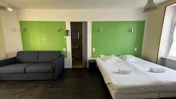 A room with a bed, a sofa, and a bathroom visible through an open door.