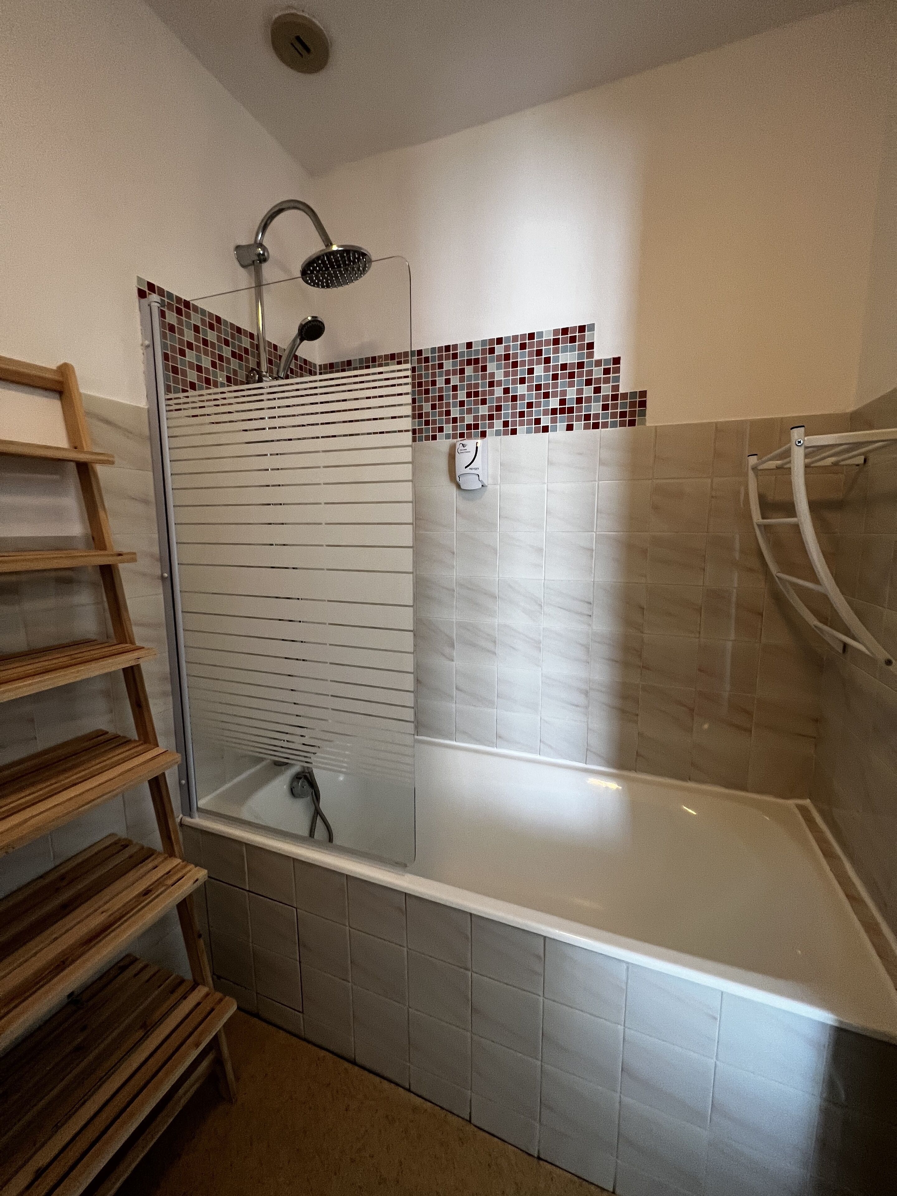 Une salle de bain avec une douche, une baignoire et une étagère en bois.