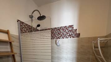 Une salle de bain avec une douche, une baignoire et une étagère en bois.