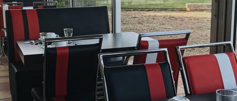 A restaurant with black and red chairs, a table with a cup, a glass, and a spoon.