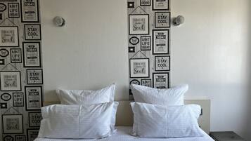 Una habitación de hotel con una cama, dos almohadas y una pared decorada con citas inspiradoras.