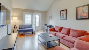 A spacious living room with a blue sofa, a red sofa, a coffee table, and a ceiling fan. - Bright & Fresh - Large Backyard - Mins to Broadway (Nashville)