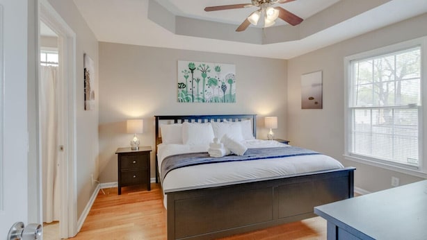 A bedroom with a bed, nightstands, a ceiling fan, artwork, and a window. - Bright & Fresh - Large Backyard - Mins to Broadway (Nashville)