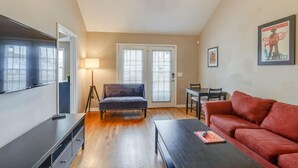 A living room with a sofa, a coffee table, a TV, and a dining area with chairs. - Bright & Fresh - Large Backyard - Mins to Broadway (Nashville)