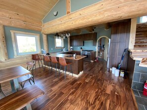 Una cocina amplia con una isla de madera, taburetes de bar y un área de comedor.