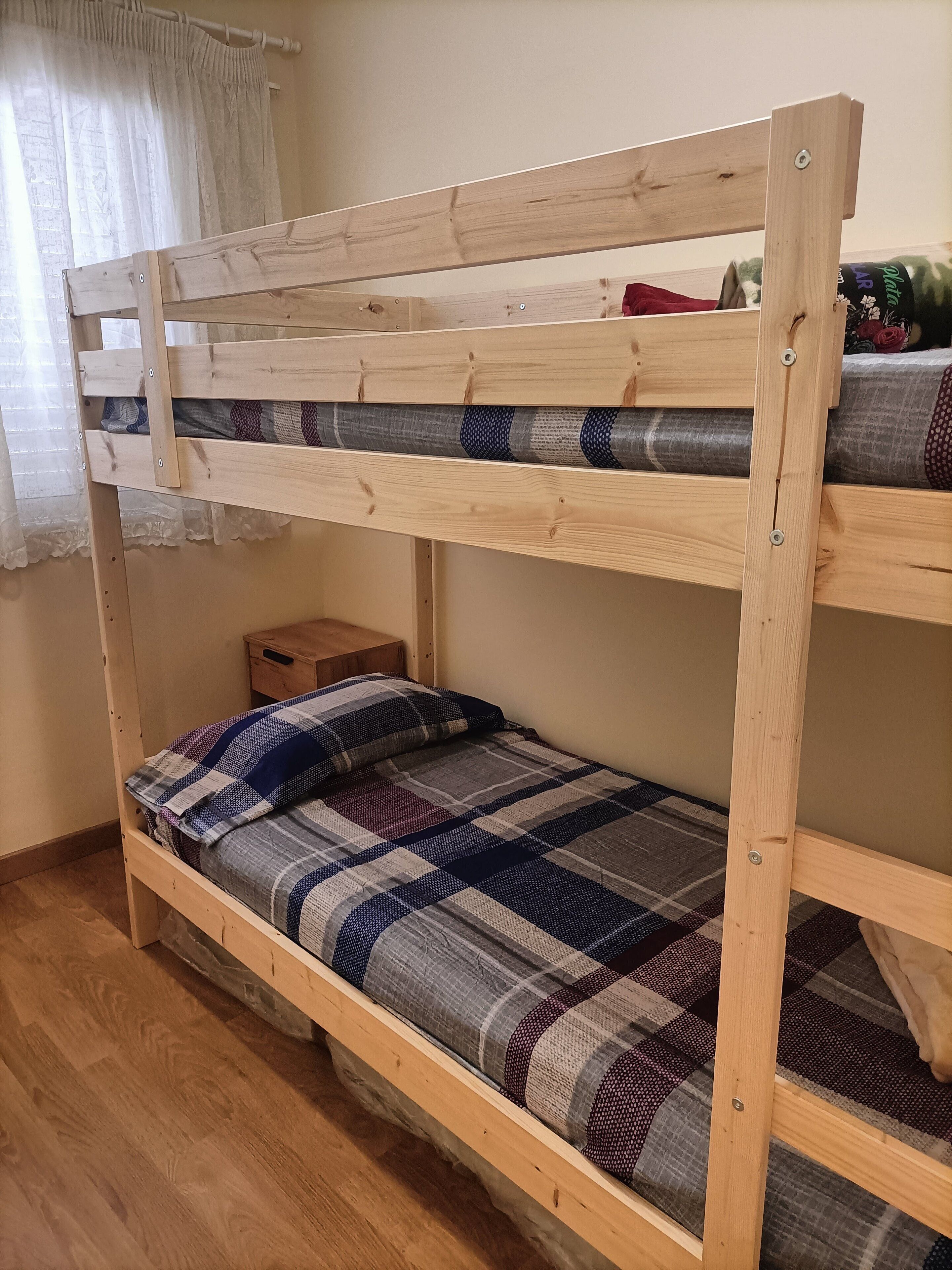 Un lit superposé avec une structure en bois et une literie à carreaux.