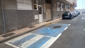 A building with a parking area, a blue handicapped parking space, and a sign indicating a reserved area.