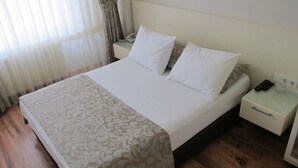 A hotel room with a bed, a bedside table with a phone, and a nightstand with a lamp. - Kadikoy Sahra Otel (Istanbul)