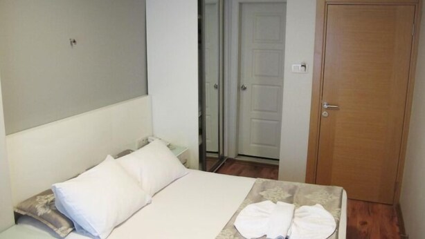 A bedroom with a bed, a wooden door, and a white wall. - Kadikoy Sahra Otel (Istanbul)