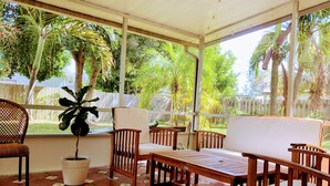 A covered patio area with wooden furniture and a potted plant.