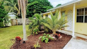 A house with a covered porch, a fenced yard, and various plants.