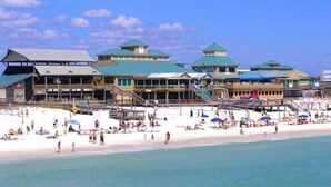A beachside resort with multiple buildings, a sandy beach, and a pier.