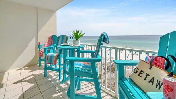 A balcony with turquoise chairs, a small table, and a 'GETAWAY' sign.
