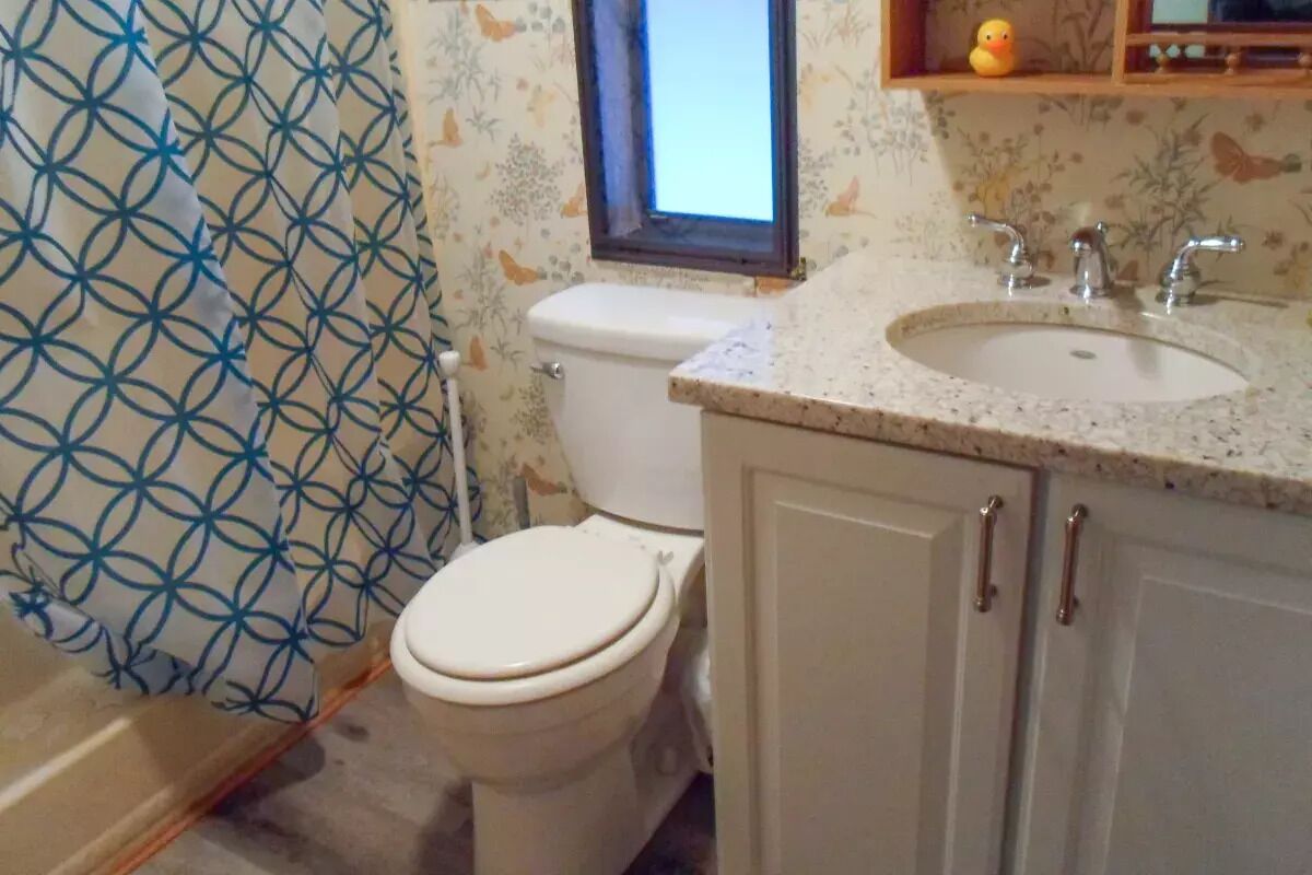 Een badkamer met een toilet, een wastafel en een raam.