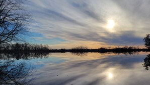 Un lac paisible où se reflètent les arbres et où le ciel est dégagé.