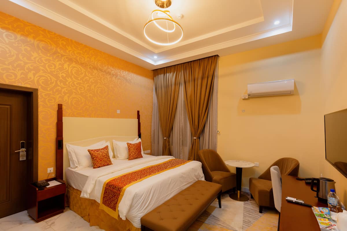 Une chambre d’hôtel avec un grand lit, un bureau, une chaise, une petite table et un appareil de climatisation.