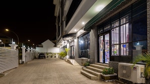 A paved driveway leading to a building with a large window and a GREE air conditioning unit. - Reno Apartments Abuja (Abuja)
