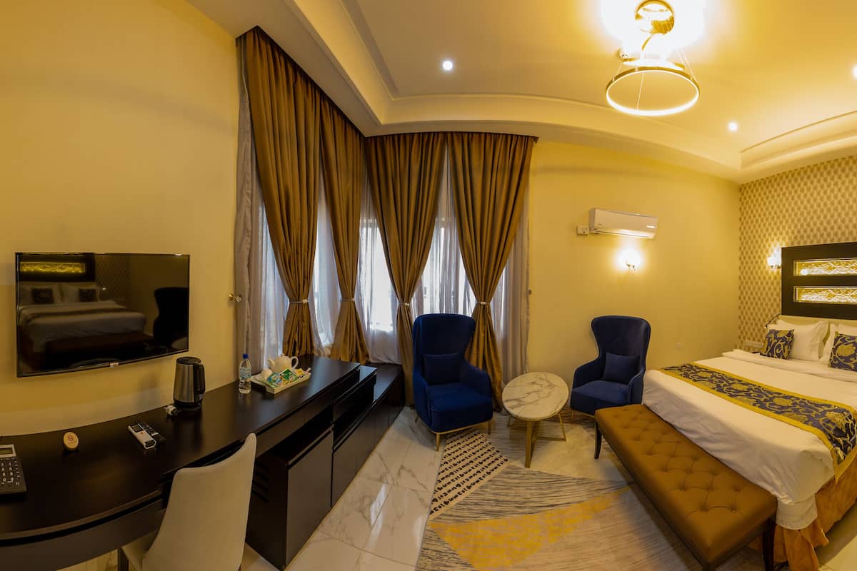 Une chambre d’hôtel comprenant un lit, un bureau, une chaise, une petite table ronde et un téléviseur.
