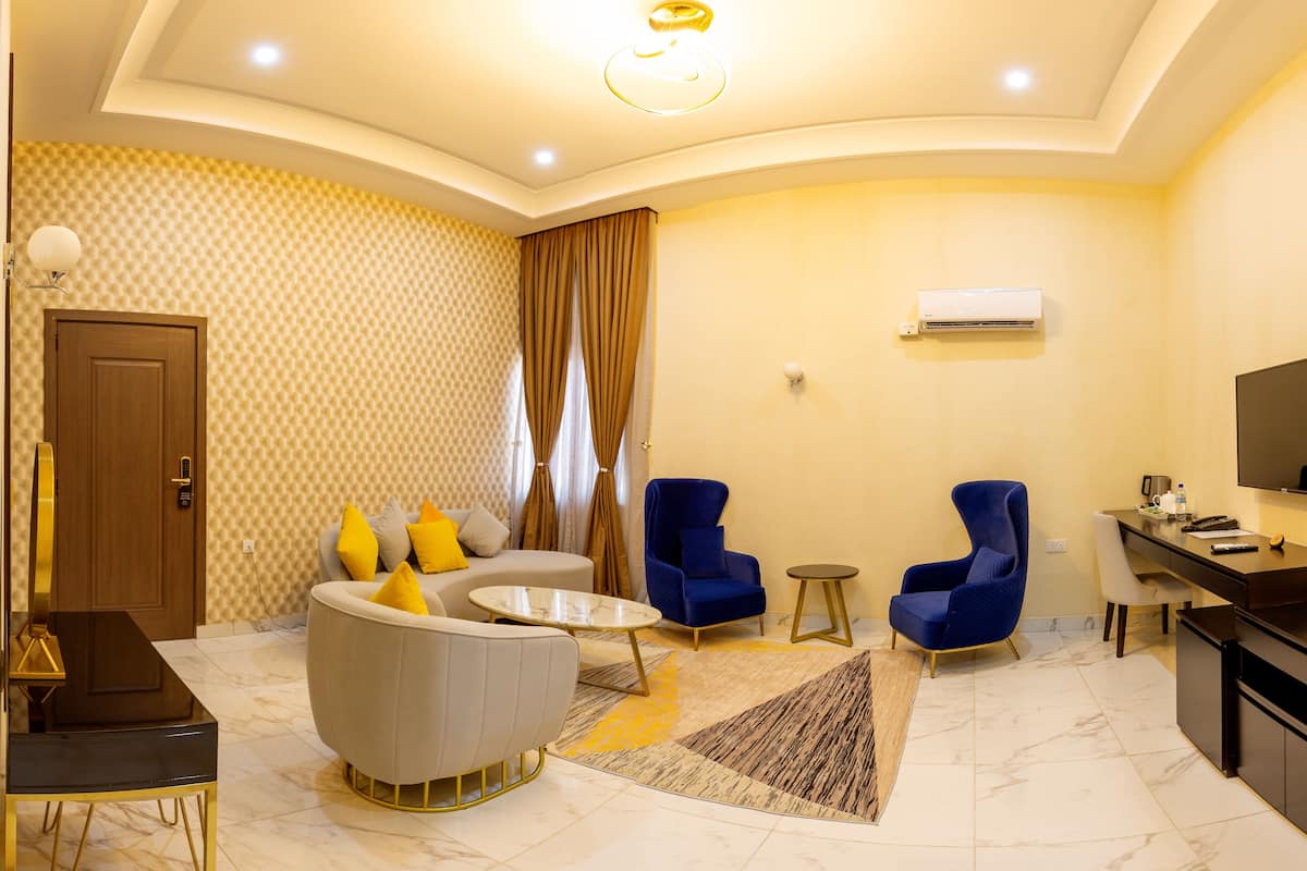 Un salon moderne comprenant un canapé, deux fauteuils, une table basse et un téléviseur.