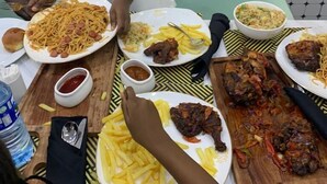 A dining table with various dishes including spaghetti, fries, and meat. - Reno Apartments Abuja (Abuja)