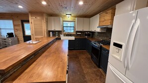Une cuisine avec des meubles de rangement en bois, un îlot central, une cuisinière et un réfrigérateur.
