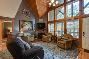 A cozy living room with a fireplace, comfortable seating, and large windows.
