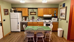 Una cocina compacta con armarios de madera, un refrigerador, una estufa y una mesa de comedor con sillas.