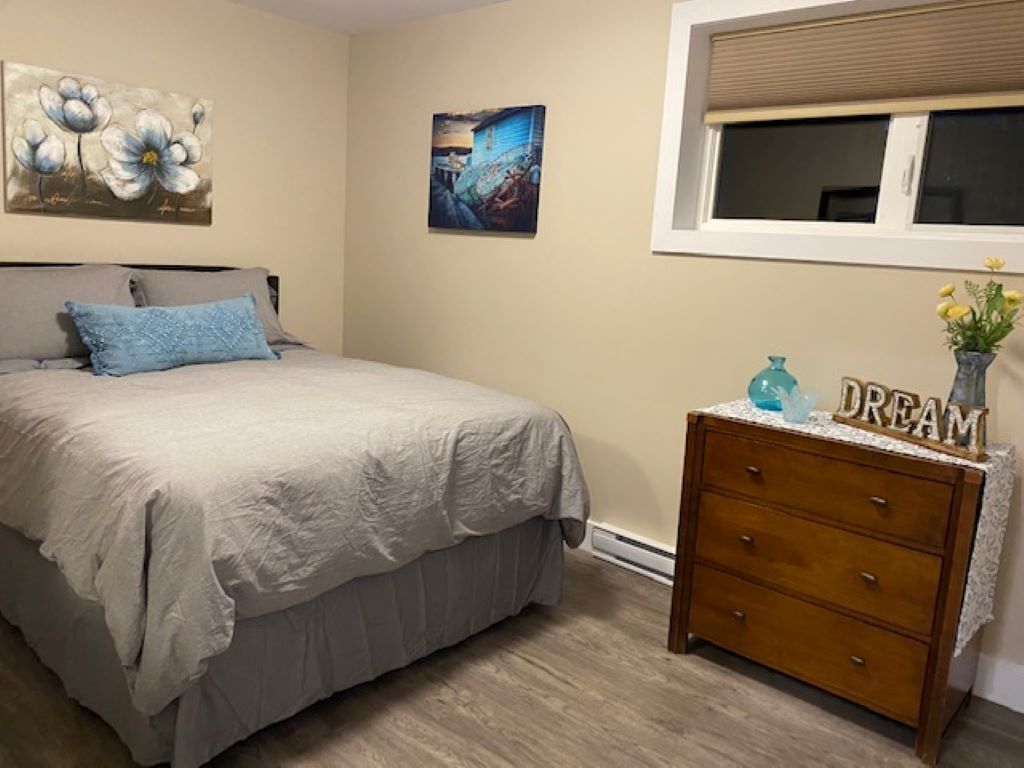 A bedroom with a bed, a dresser, and two wall art pieces.