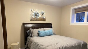 Een slaapkamer met een bed, een hoofdeinde, een raam en een aan de muur hangend kunstwerk.