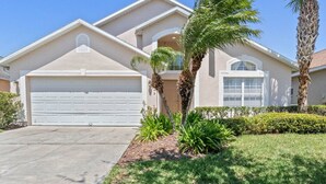 Une maison de plain-pied avec un garage, des palmiers et une pelouse bien entretenue.